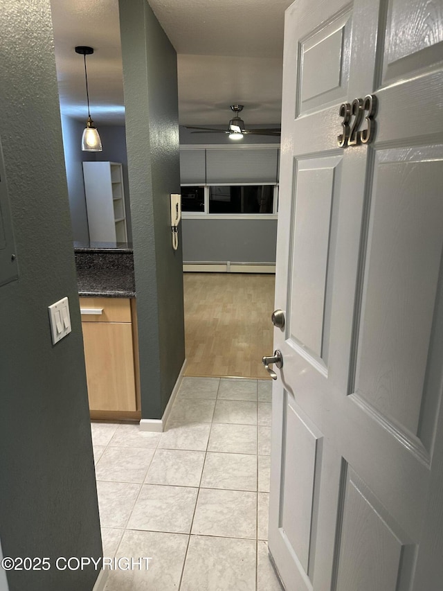 corridor with light tile patterned floors and baseboard heating