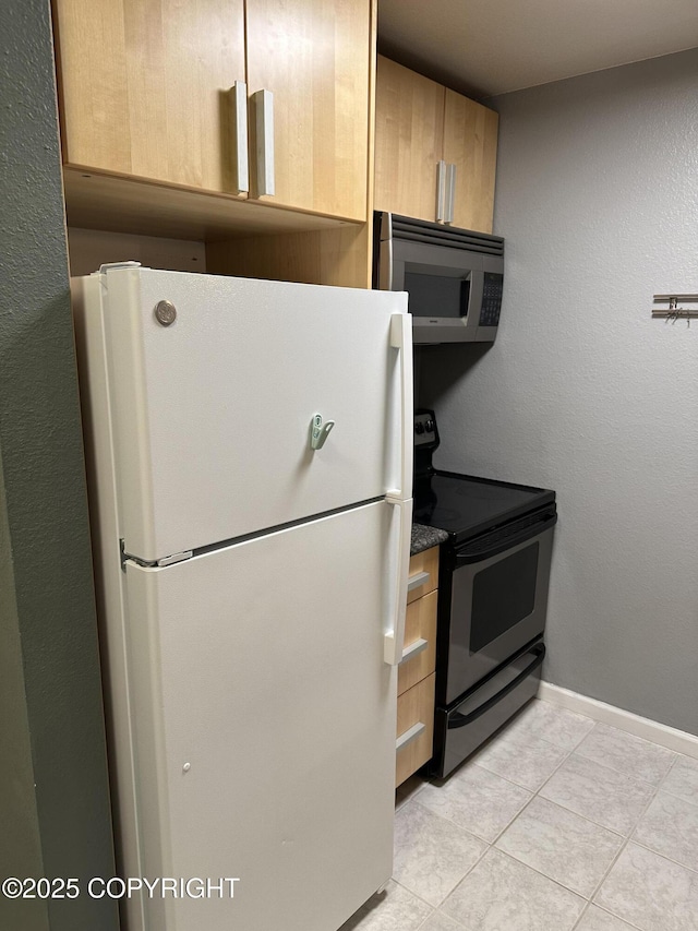 kitchen featuring light brown cabinetry, light tile patterned floors, appliances with stainless steel finishes, and baseboards