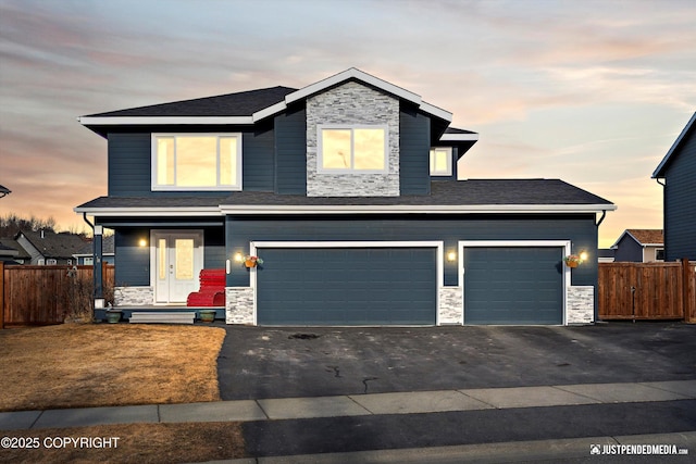 view of front of home with aphalt driveway, fence, and stone siding