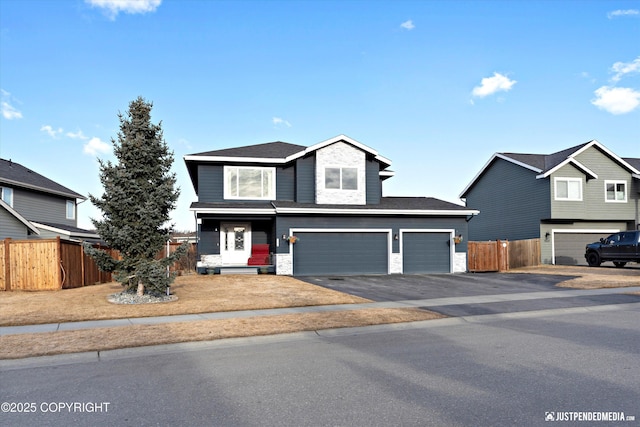 traditional-style home featuring an attached garage, driveway, and fence