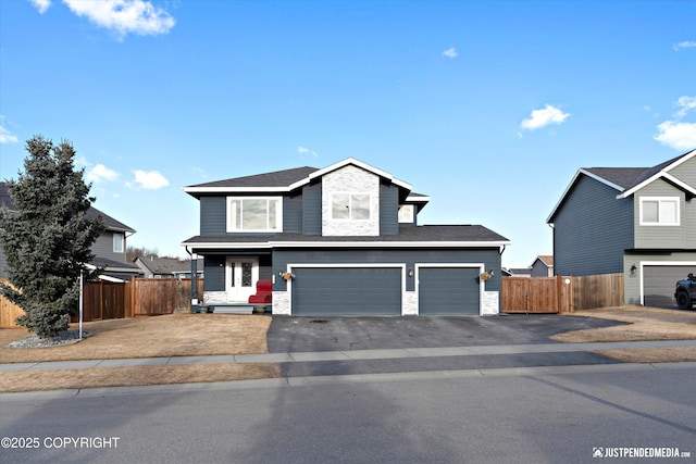 traditional-style home featuring aphalt driveway, stone siding, and fence