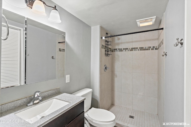 full bath featuring toilet, vanity, and a tile shower