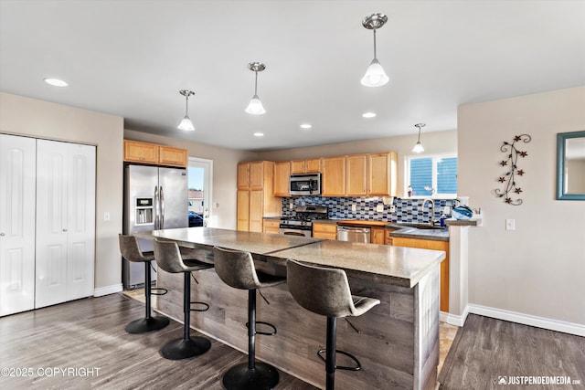 kitchen with light brown cabinetry, a sink, wood finished floors, appliances with stainless steel finishes, and decorative backsplash