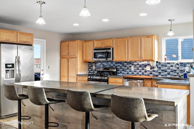 kitchen with a sink, a breakfast bar area, backsplash, and stainless steel appliances