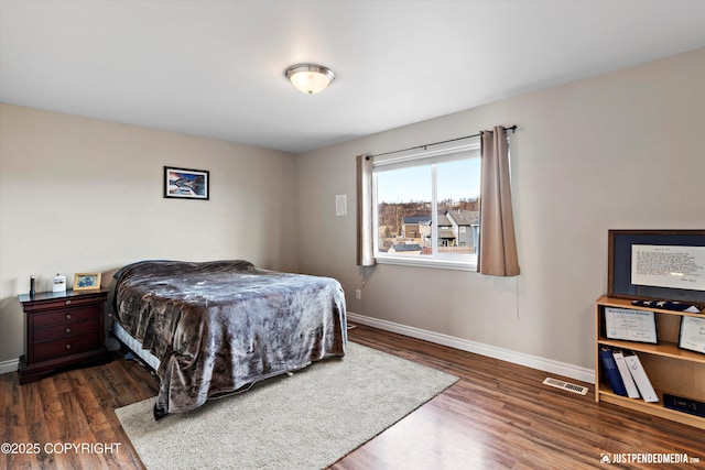 bedroom with visible vents, baseboards, and wood finished floors