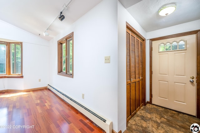 entrance foyer featuring a wealth of natural light, lofted ceiling, baseboard heating, and dark wood-type flooring