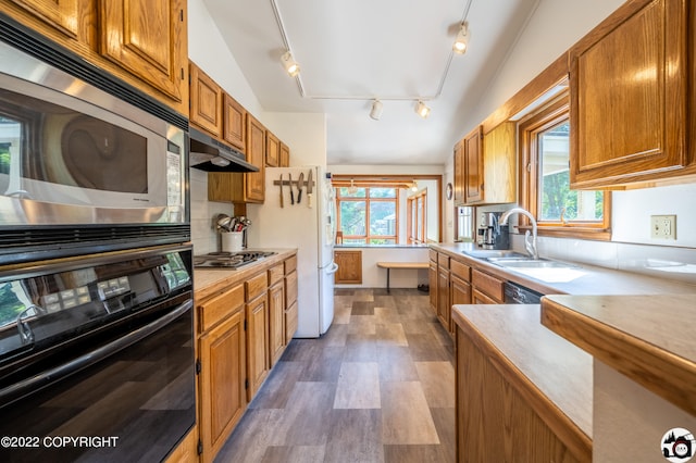 kitchen featuring double oven, a healthy amount of sunlight, under cabinet range hood, and a sink