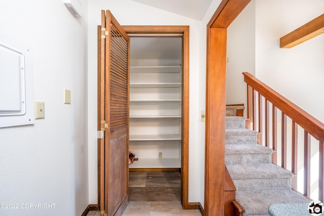 stairway featuring electric panel and lofted ceiling