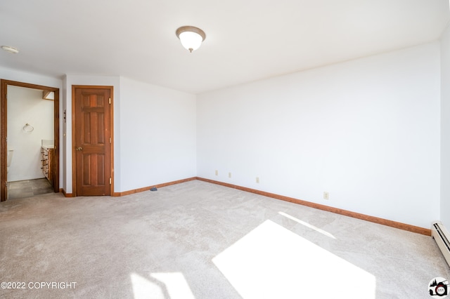 spare room featuring light colored carpet, baseboards, and baseboard heating