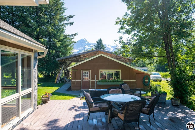 wooden deck featuring a mountain view, a yard, outdoor dining space, and an outdoor structure