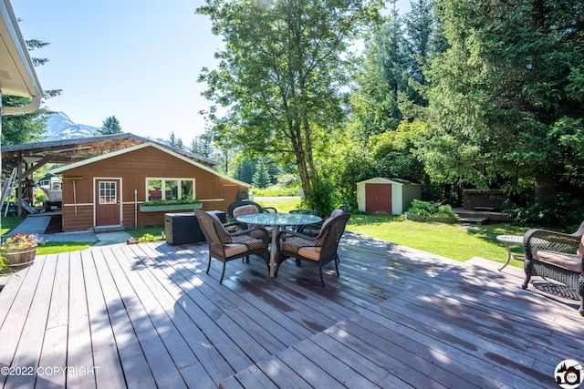 wooden terrace featuring outdoor dining space, an outdoor structure, a lawn, and a shed