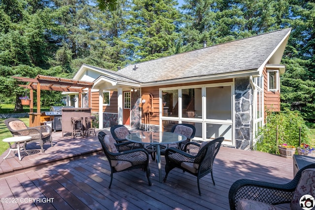 wooden deck with outdoor dining space, area for grilling, and a pergola