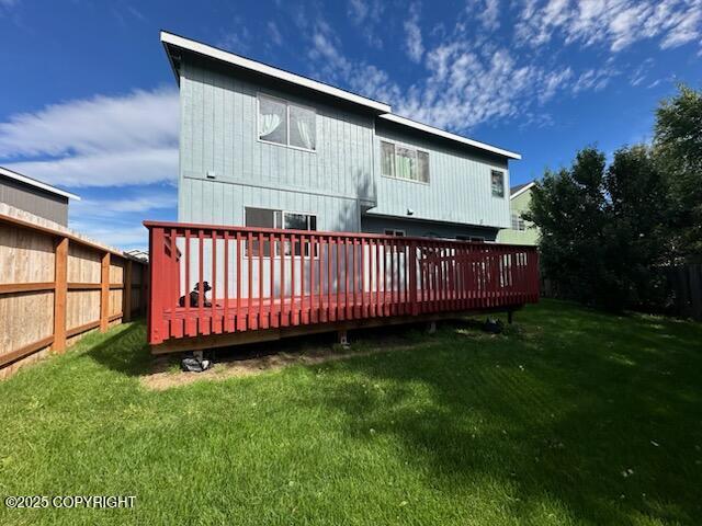 rear view of property featuring a lawn, a deck, and fence