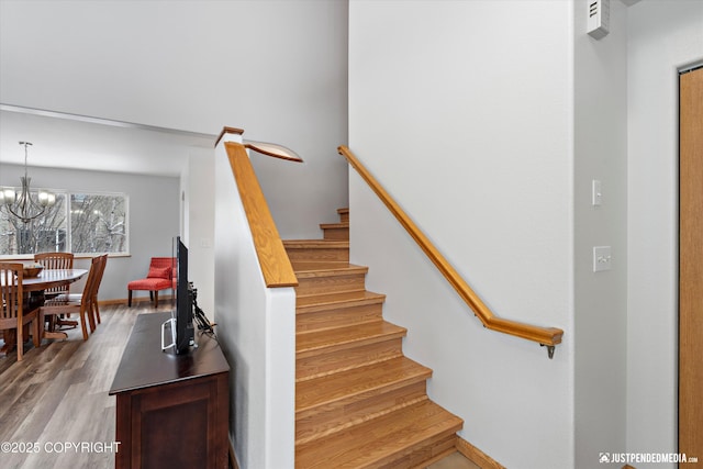 stairs with baseboards, an inviting chandelier, and wood finished floors