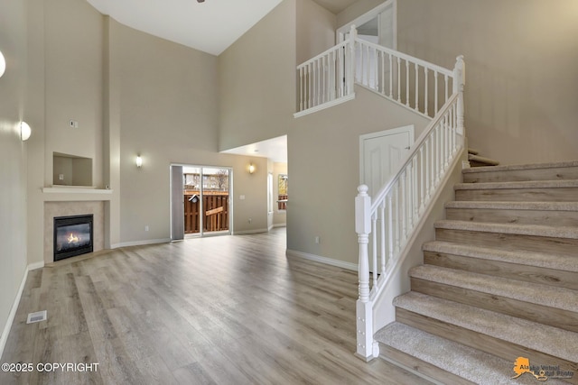 1091 Northpointe Bluff Dr, Anchorage, AK 99501 - unfurnished living room with wood finished floors, a towering ceiling, stairway, and a tiled fireplace