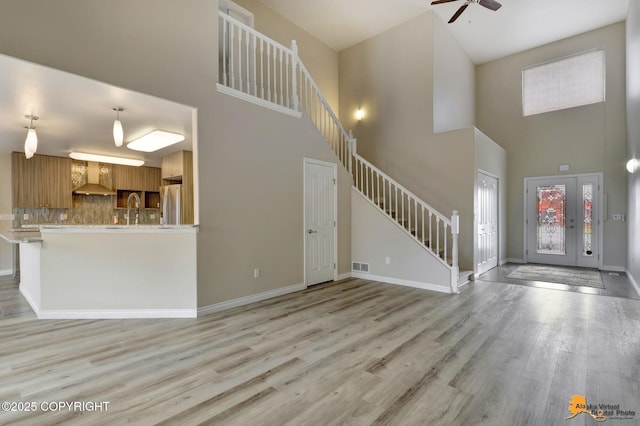 1091 Northpointe Bluff Dr, Anchorage, AK 99501 - entrance foyer with a high ceiling, stairs, a ceiling fan, and light wood-style floors
