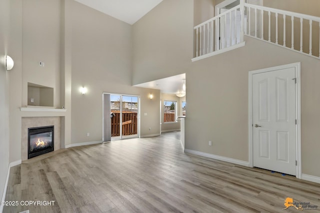 1091 Northpointe Bluff Dr, Anchorage, AK 99501 - unfurnished living room with high vaulted ceiling, a tiled fireplace, and wood finished floors