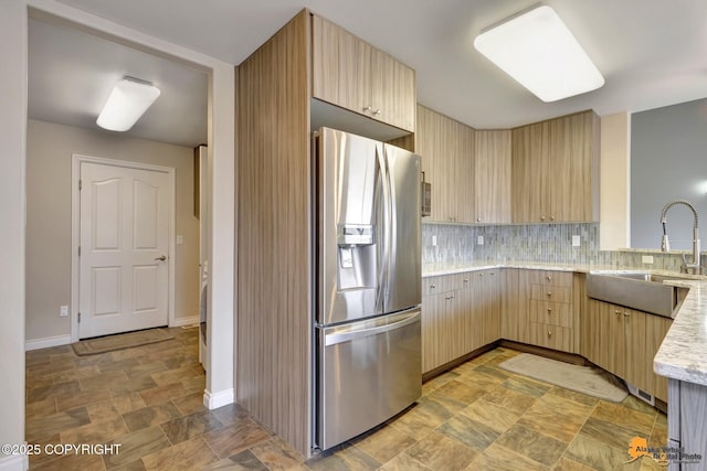 1091 Northpointe Bluff Dr, Anchorage, AK 99501 - kitchen featuring stainless steel fridge with ice dispenser, light brown cabinetry, stone finish flooring, tasteful backsplash, and light stone countertops
