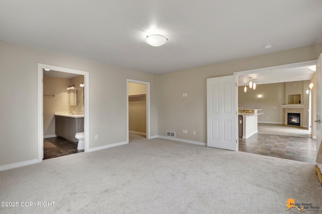1091 Northpointe Bluff Dr, Anchorage, AK 99501 - unfurnished bedroom featuring carpet floors, a spacious closet, a glass covered fireplace, ensuite bathroom, and a closet