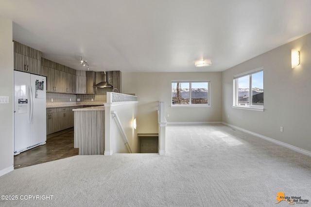 1091 Northpointe Bluff Dr, Anchorage, AK 99501 - kitchen with white fridge with ice dispenser, wall chimney range hood, light countertops, open floor plan, and decorative backsplash