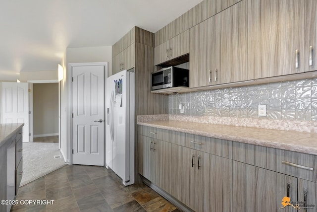 1091 Northpointe Bluff Dr, Anchorage, AK 99501 - kitchen featuring white fridge with ice dispenser, stainless steel microwave, tasteful backsplash, modern cabinets, and light stone countertops