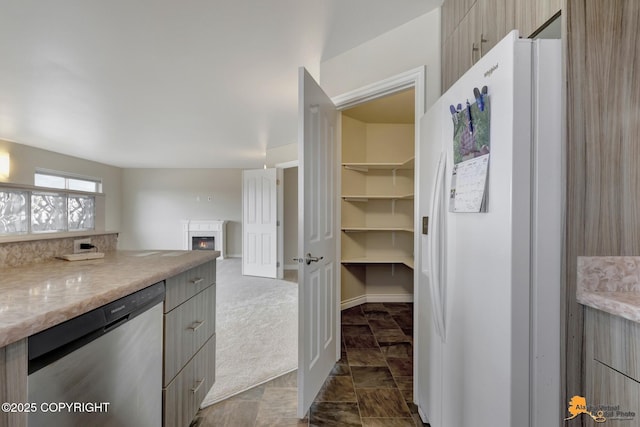 1091 Northpointe Bluff Dr, Anchorage, AK 99501 - kitchen featuring white refrigerator with ice dispenser, stainless steel dishwasher, a warm lit fireplace, gray cabinetry, and modern cabinets