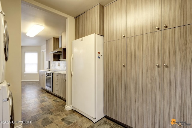 1091 Northpointe Bluff Dr, Anchorage, AK 99501 - kitchen featuring freestanding refrigerator, oven, stacked washing machine and dryer, backsplash, and light countertops