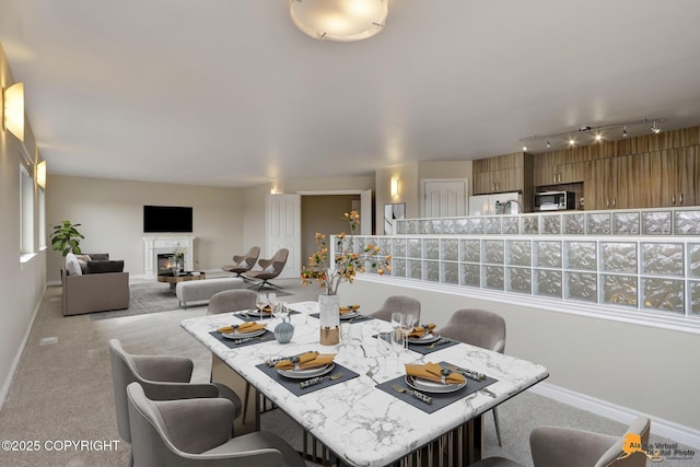 1091 Northpointe Bluff Dr, Anchorage, AK 99501 - dining space featuring carpet flooring, a glass covered fireplace, and track lighting