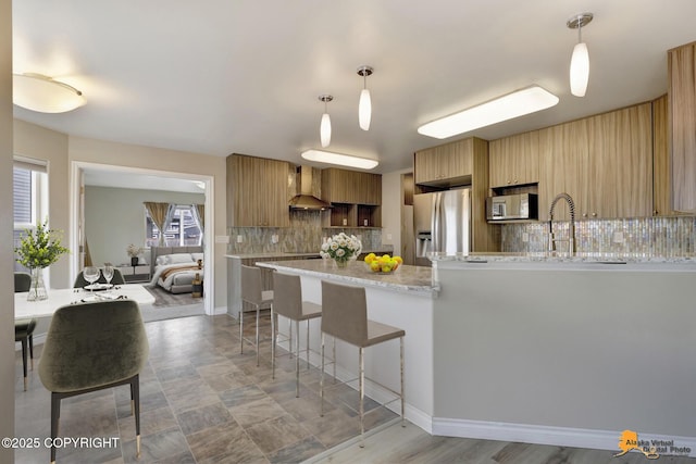 1091 Northpointe Bluff Dr, Anchorage, AK 99501 - kitchen featuring appliances with stainless steel finishes, wall chimney range hood, tasteful backsplash, a peninsula, and healthy amount of natural light