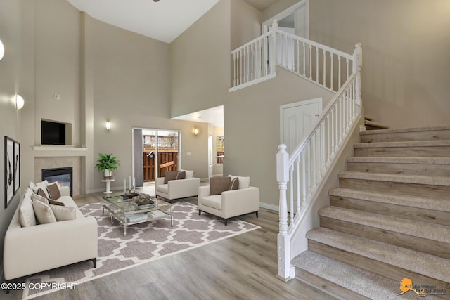 1091 Northpointe Bluff Dr, Anchorage, AK 99501 - living area with a high ceiling, stairs, wood finished floors, and a glass covered fireplace