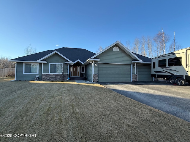 view of front facade with a garage, stone siding, a front yard, and driveway