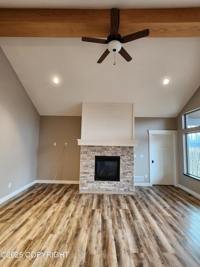 unfurnished living room featuring a fireplace, lofted ceiling with beams, wood finished floors, and baseboards