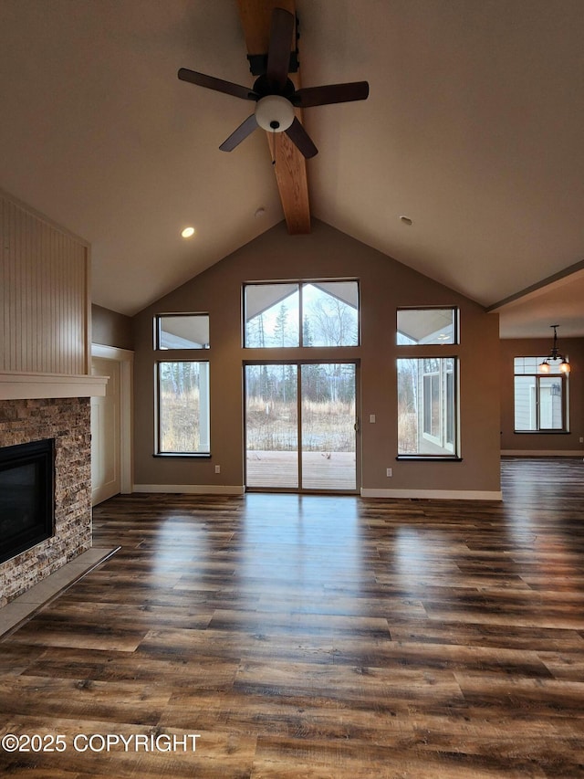 unfurnished living room with beam ceiling, high vaulted ceiling, a ceiling fan, a stone fireplace, and dark wood-style flooring