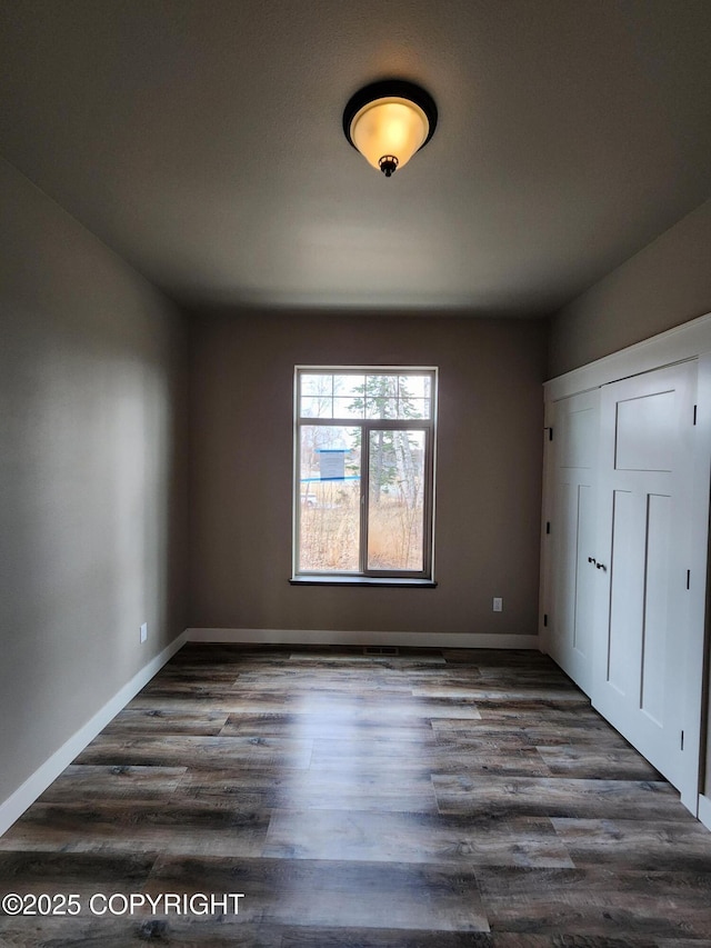 unfurnished bedroom featuring baseboards and dark wood finished floors