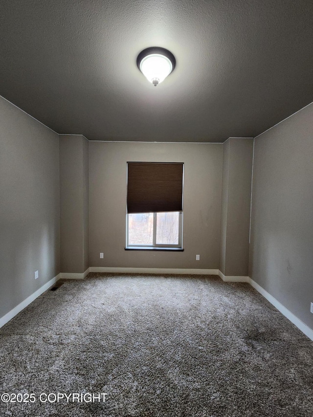 carpeted empty room with a textured ceiling and baseboards