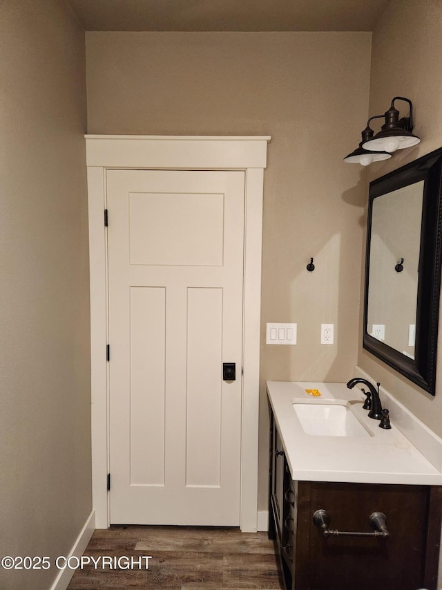 bathroom with vanity, wood finished floors, and baseboards