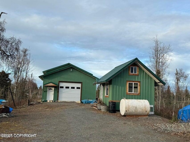 chalet / cabin featuring a detached garage, central AC unit, an outbuilding, driveway, and heating fuel