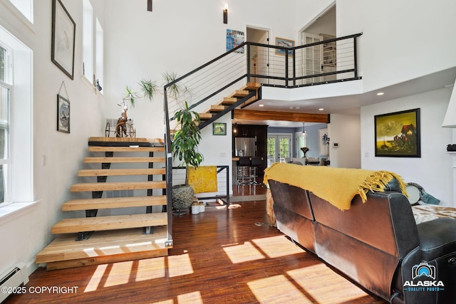 19136 S Birchwood Loop Rd, Chugiak, AK 99567 - living room with a baseboard radiator, wood finished floors, a towering ceiling, and stairs