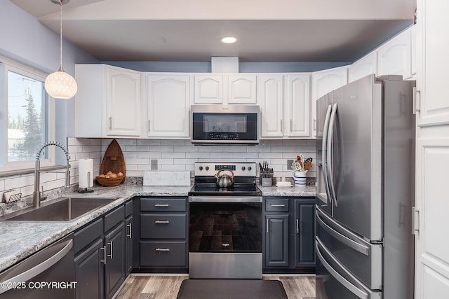 kitchen with a sink, stainless steel appliances, light wood-type flooring, and white cabinetry