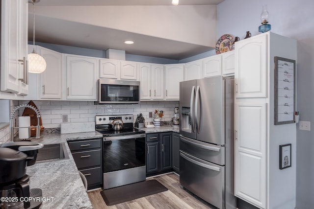 kitchen featuring decorative backsplash, light wood-style flooring, appliances with stainless steel finishes, white cabinetry, and a sink