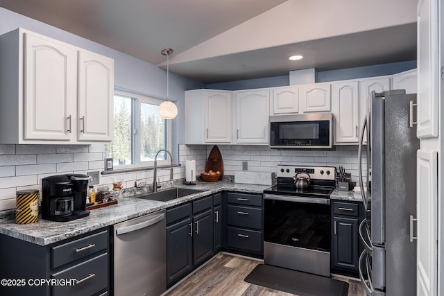 kitchen featuring vaulted ceiling, appliances with stainless steel finishes, white cabinetry, and a sink