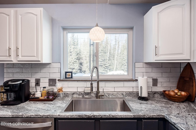 kitchen featuring stainless steel dishwasher, backsplash, white cabinetry, and a sink