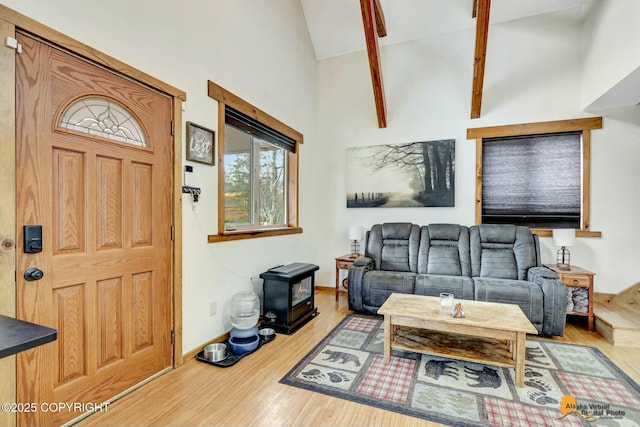 living area with baseboards, high vaulted ceiling, wood finished floors, and a wood stove