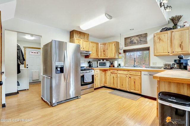 kitchen with light brown cabinetry, a sink, under cabinet range hood, stainless steel appliances, and light countertops