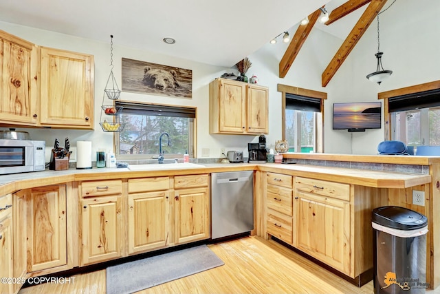 kitchen featuring light wood finished floors, lofted ceiling with beams, a sink, light brown cabinetry, and stainless steel appliances