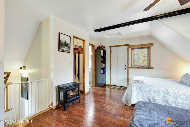 bedroom featuring vaulted ceiling, a wood stove, baseboards, and wood finished floors