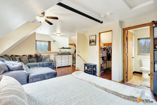 bedroom with a spacious closet, ensuite bath, baseboards, and wood finished floors