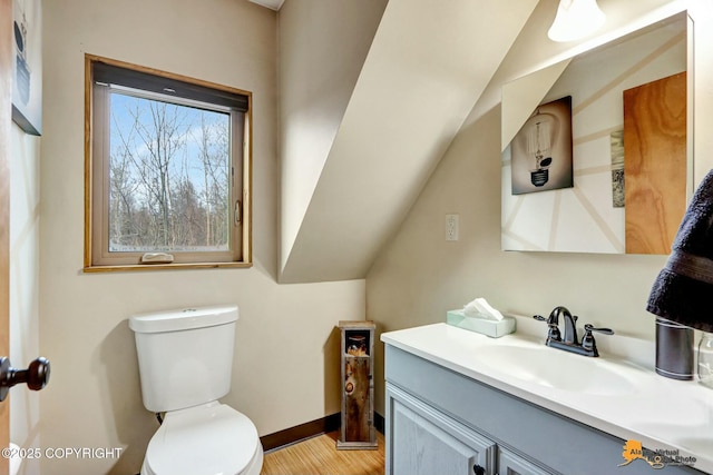 bathroom featuring vanity, toilet, wood finished floors, and baseboards