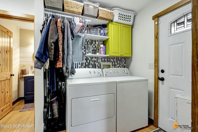 washroom featuring cabinet space, light wood-style floors, and washing machine and dryer