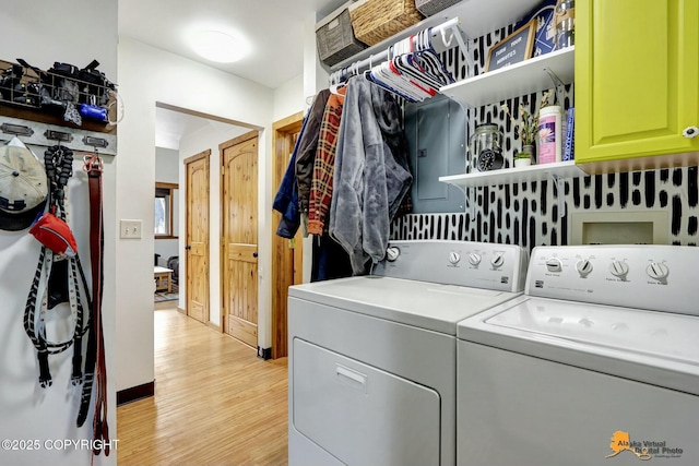 clothes washing area featuring cabinet space, light wood-style floors, and washing machine and dryer